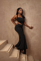 Woman in a black dress standing on a staircase against a beige wall