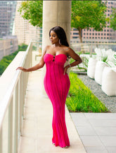 Woman in a pink dress standing on a balcony with a cityscape background