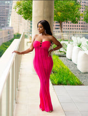 Woman in a pink dress standing on a balcony with a cityscape background