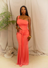 Woman in a coral one-shoulder dress standing against a neutral background