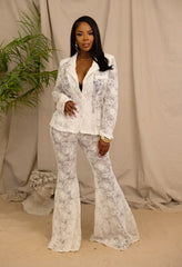 Woman wearing a white lace outfit against a beige curtain background