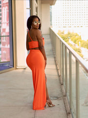 Woman in an orange dress standing on a balcony with a cityscape background