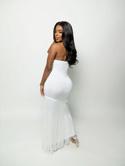 Woman wearing a white strapless dress with fringe details on a plain background