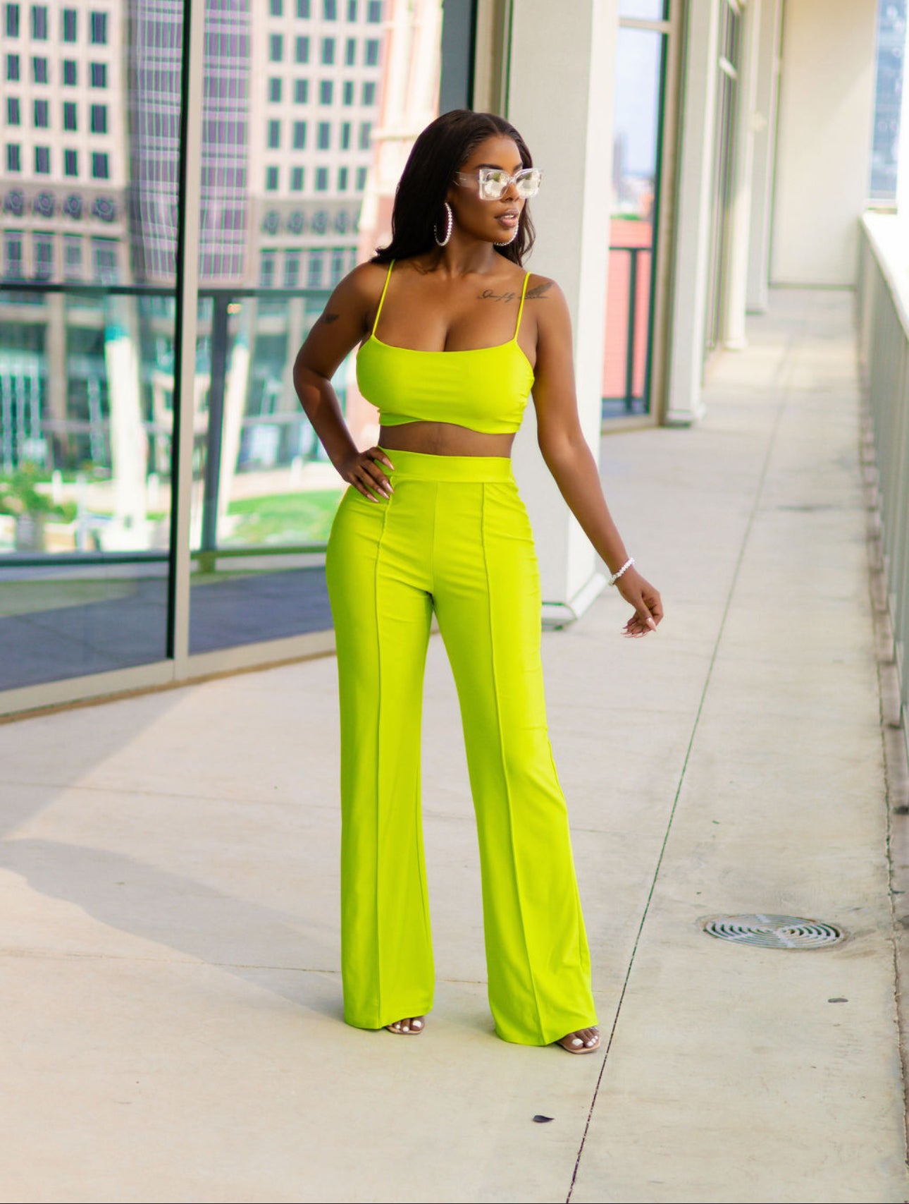 Woman in a neon green outfit standing on a city sidewalk.