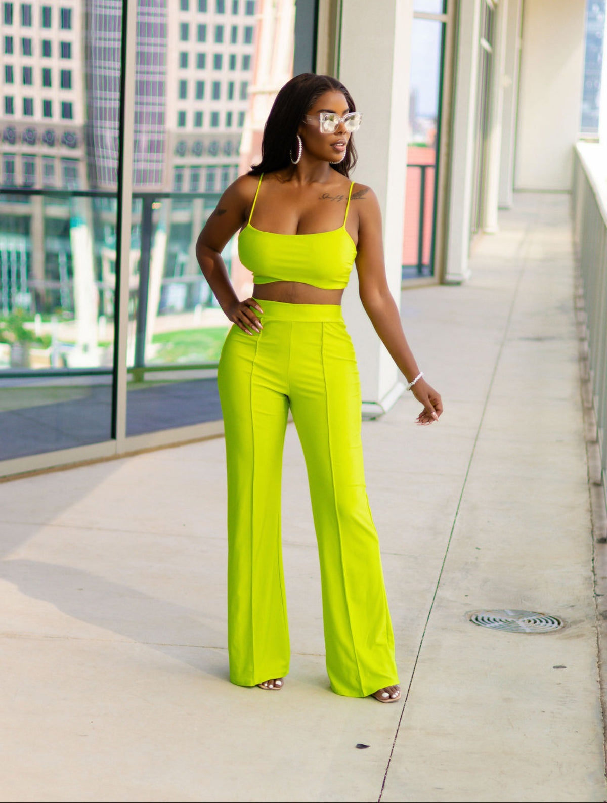 Woman in a neon green outfit standing on a city sidewalk.