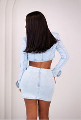 Women wearing a light blue denim jacket and skirt set on a plain background