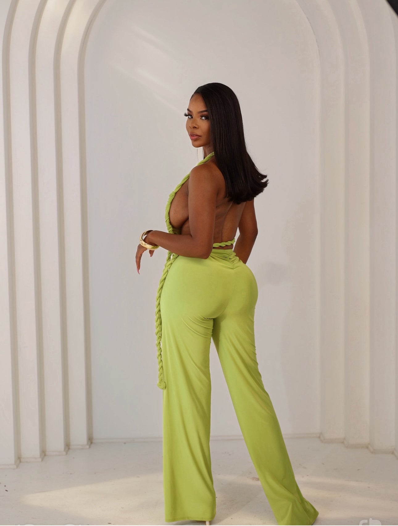 Woman wearing a bright green jumpsuit with a white background